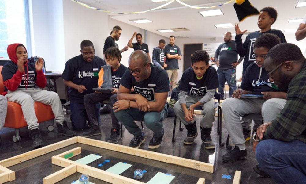 Volunteers demonstrating practical examples to students at a Black Boys Code Workshop